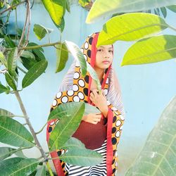 Portrait of girl wearing traditional clothing while standing against plant