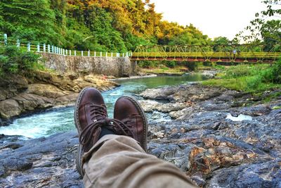 Low section of man sitting at waterfall