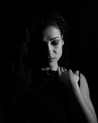 Portrait of young woman against black background