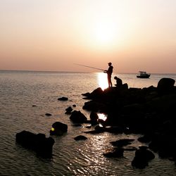 A fisherman catching fish while the sun is setting