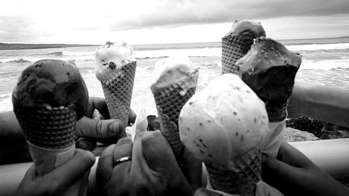 Cropped hands of people holding ice creams on beach