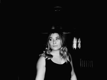 Young woman looking away while standing in darkroom