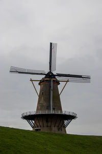 Traditional windmill on field against sky