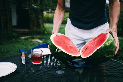 Midsection of man holding watermelon at table