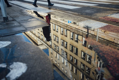 Reflection of person in puddle walking on street