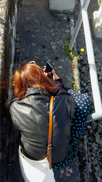 Rear view of woman photographing with mobile phone