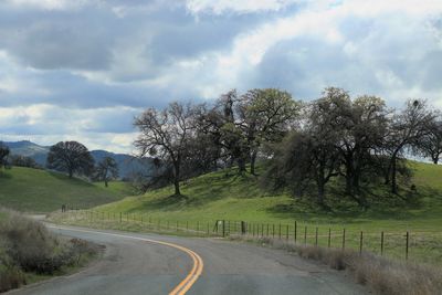 Scenic view of road amidst trees against sky