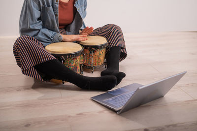 Low section of woman playing bongo drums