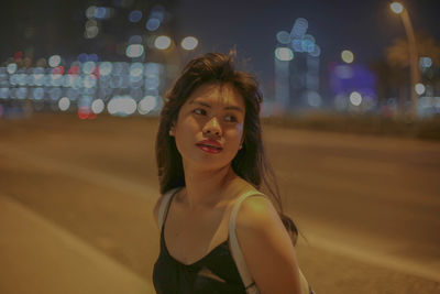 Portrait of beautiful woman standing on road at night