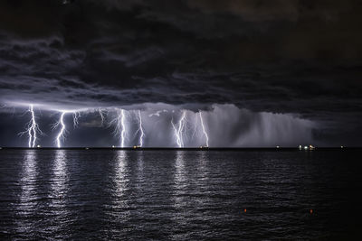 Scenic view of sea against storm clouds at night