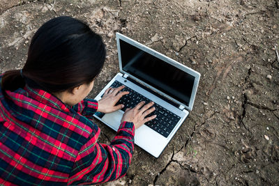 Rear view of woman using laptop while sitting on field