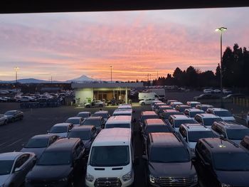 Cars in parking lot against sky during sunset