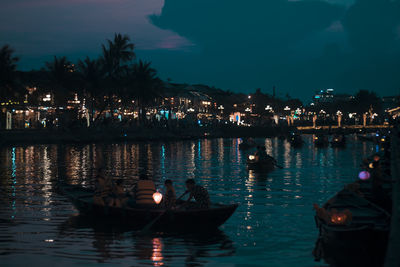 Boats in lake against illuminated city at night