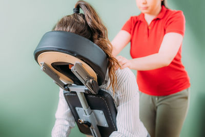 Female employee sitting on a portable massage chair in business office. therapist massaging 