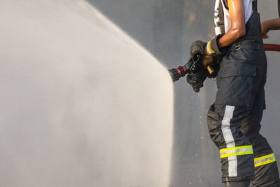 Fireman or firefighter spraying water from big water hose to prevent fire