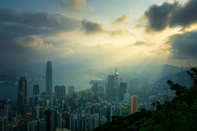 Aerial view of buildings in city against cloudy sky
