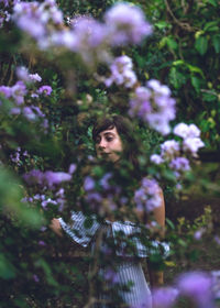 Portrait of beautiful young woman standing by tree