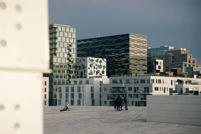 People walking on modern building in city against sky