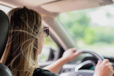 Young woman wearing sunglasses while driving car