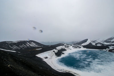 Scenic view of sea by snowcapped mountain against sky