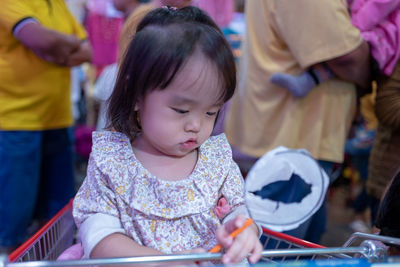 Close-up of baby girl sitting in shopping cart at store