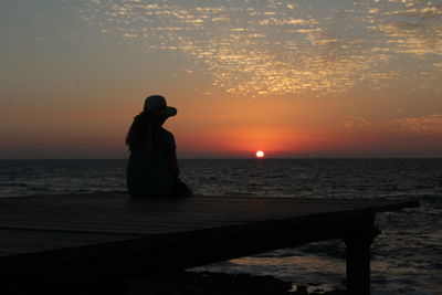 Rear view of woman contemplating sunset at the seaside