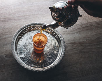 High angle view of person pouring drink in glass on table