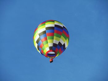 Low angle view of colorful hot air balloon flying against clear blue sky