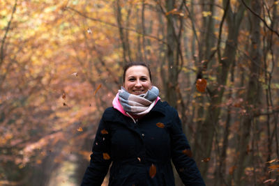 Portrait of smiling woman in forest during autumn