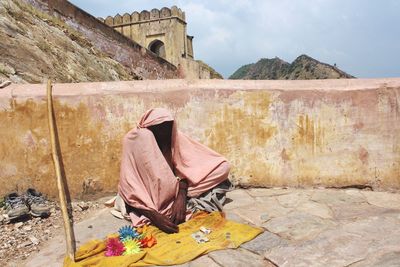 Beggar sitting by retaining wall