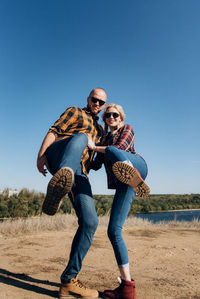 Full length of young couple on land against clear sky