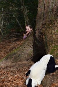 Person in costume playing hide and seek with girl at tree in forest