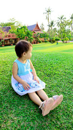 Girl looking away while sitting on field