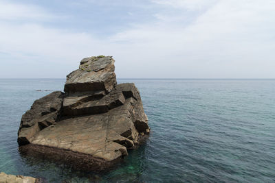 Rock formation by sea against sky