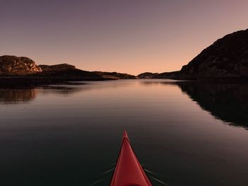 Cropped kayak on calm lake against sky during sunset