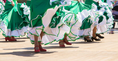 Low section of women dancing on footpath during sunny day