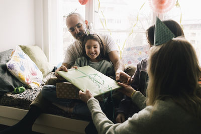 Parents giving gift to birthday girl at home