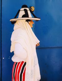 Rear view of woman standing against blue wall