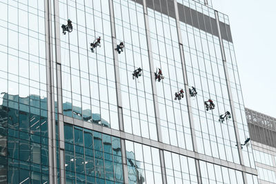 Low angle view of people working on glass window