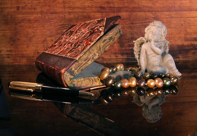 Close-up of book with angel figurine and pearl jewelry on table