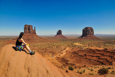 Woman sitting on rock formation at desert