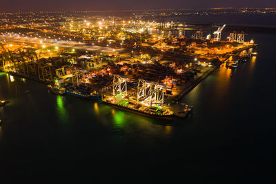 High angle view of illuminated cityscape by sea at night