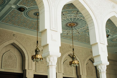 Low angle view of electric lamp hanging on ceiling of building