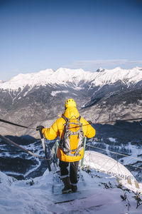 Man wearing yellow jacket hiking downhill mountains