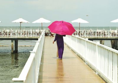 Full length of woman standing on bridge against sea