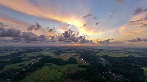 Scenic view of landscape against dramatic sky during sunset