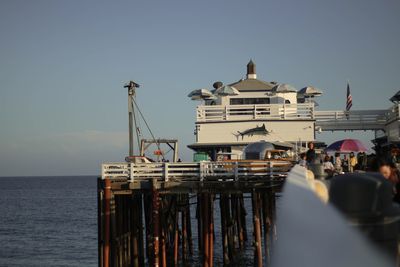 People on pier over sea against sky