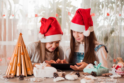  girls in christmas decorations communicate with their families through a tablet.