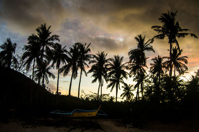 Silhouette palm trees on beach against sky at sunset