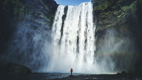Person standing against beautiful waterfall